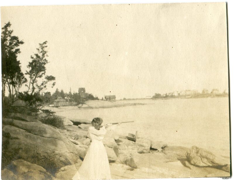 Marie Walden Sperry aims a rifle while standing on Hillside Beach