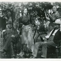 Men seated, women standing by bicycle.jpg